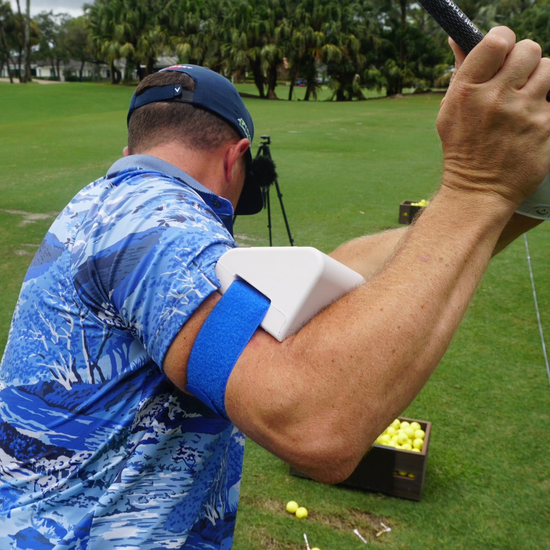 Golfer wearing the Pro-Slot Trainer on the arm during a backswing on the driving range