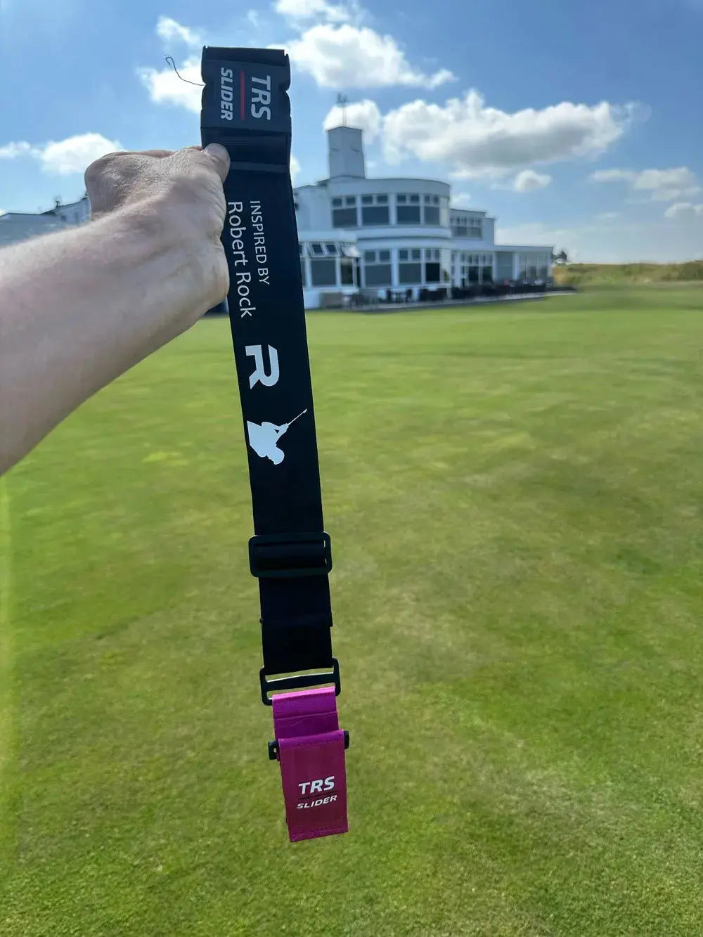 TRS Slider swing training aid held on a golf course with clubhouse in the background