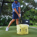 Golfer striking the Golf Impact Bag training aid on a tropical practice green