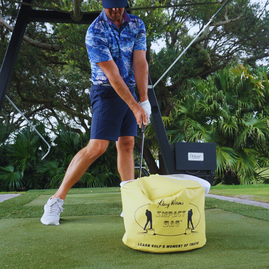 Golfer striking the Golf Impact Bag training aid on a tropical practice green