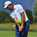 Golfer using The Connector training aid between arms and chest during a swing on the course