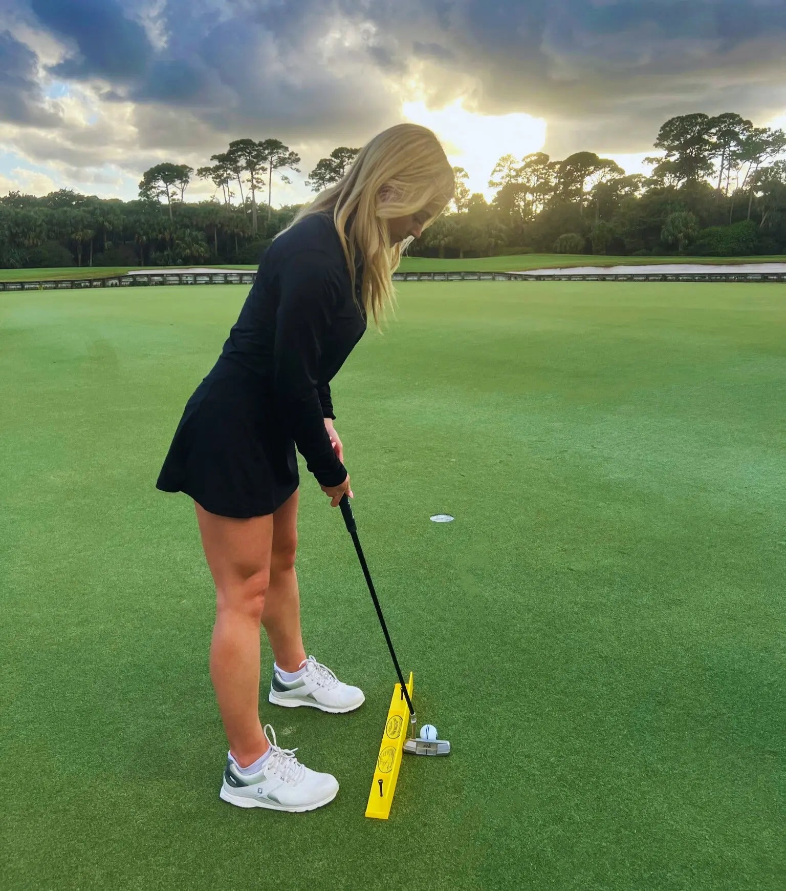 Golfer practicing putting stroke with the Putting Arc T3 on a green at sunset